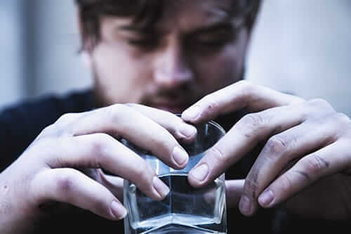 A man stares at an empty glass thinking about his options for alcohol addiction rehab centers