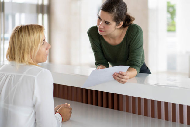 woman talking to receptionist about finding an outpatient drug treatment center